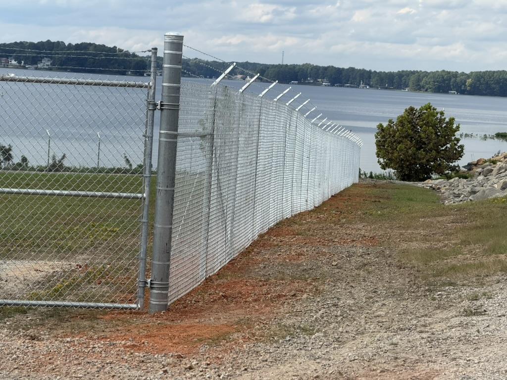 New chain-link security fence with barbed-wire outriggers installed by Ives Contracting