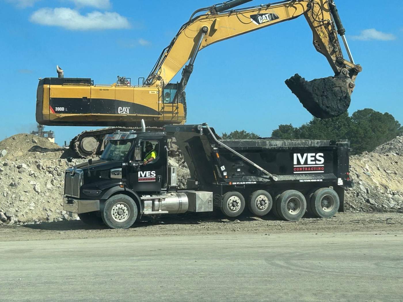 Excavator loading an Ives quint-axle dump truck